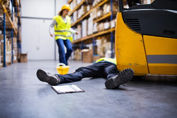 A Worker Lying on Ground Due to a Forklift Hazard Being Approached By Co-worker